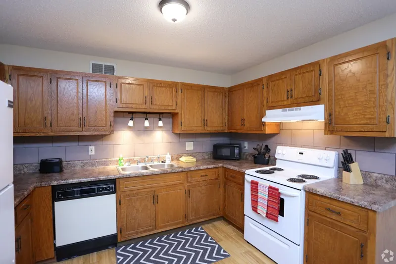 Furnished kitchen with wood cabinets and a tile backsplash